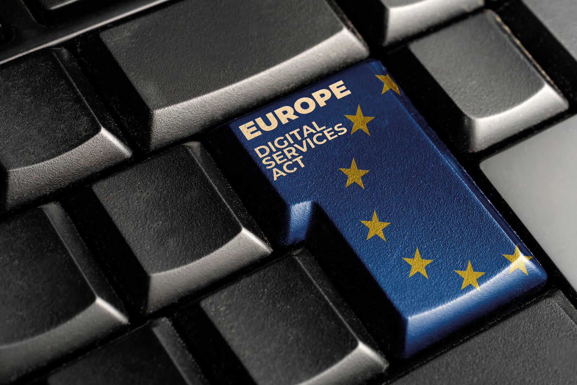 Nærbilde av et pc-tastatur, hvor enter-tasten er blå med gule stjerner og har teksten «europe, digital service act» på seg, foto.